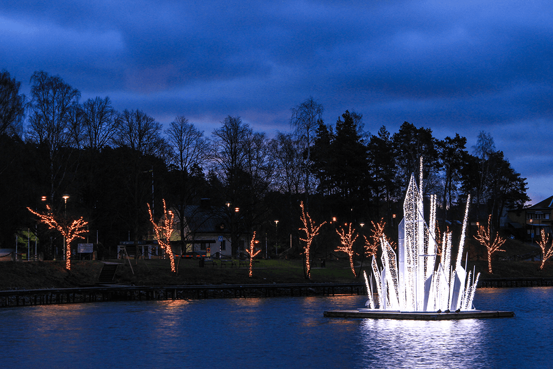 MK-Illumination-Sodertalje Träd klädda i ljusslingor. En konstgjord isskulptur i en damm.