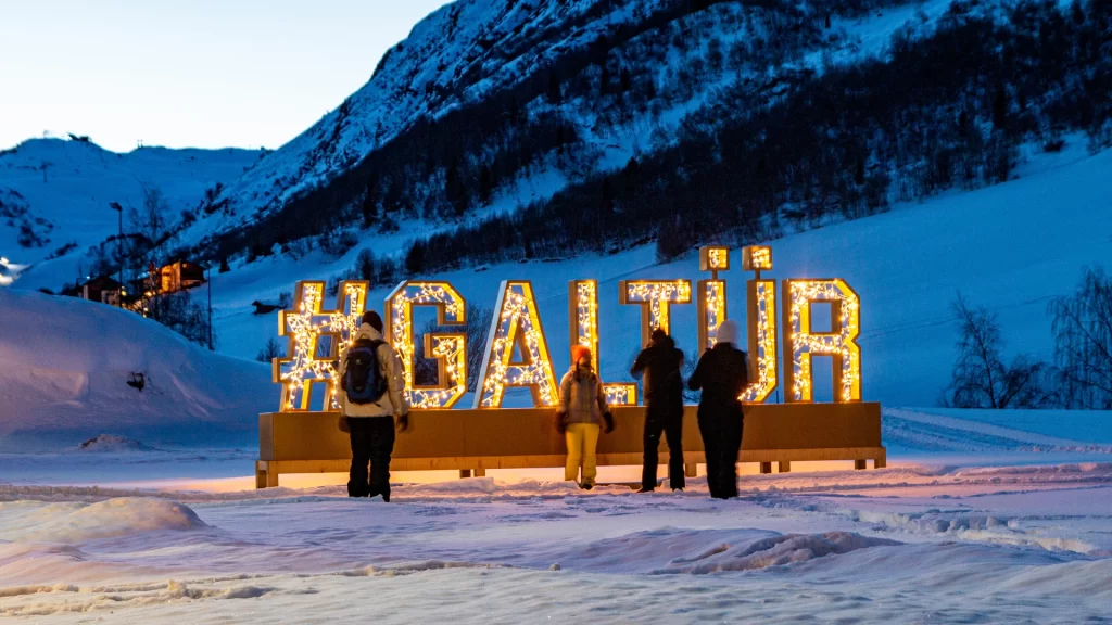 Familj som tar bilder framför stora upplysta bokstäver som bildar ordet #GALTÜR